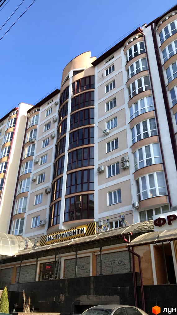 Будинок на вулиці Героїв Майдану, 53, з вигнутим фасадом та великою кількістю вікон. На першому поверсі розташовані магазини, один з яких має вивіску 