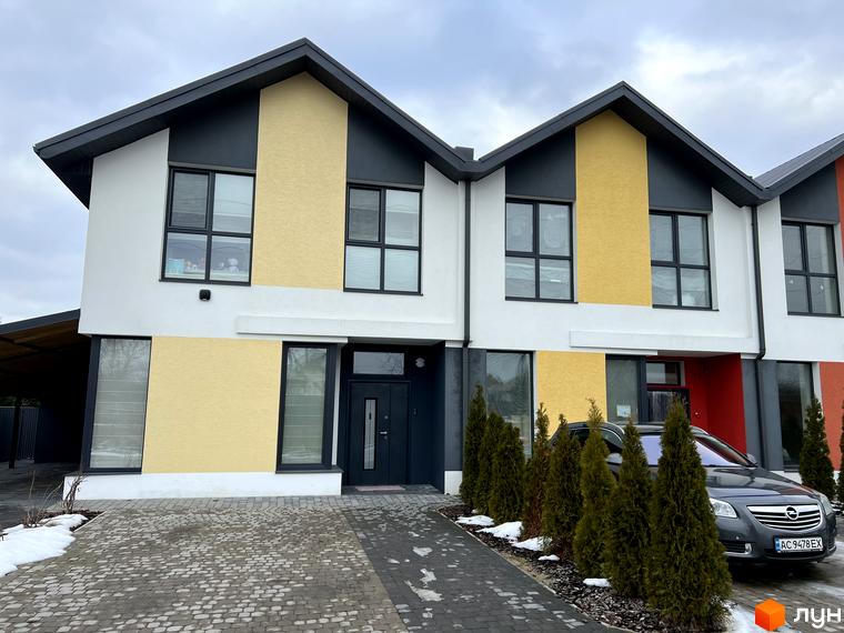 Зовнішній вигляд таунхаусів 9 YARDS з фасадами у світлих тонах. На території є бруківка, зелені насадження та припаркований автомобіль.