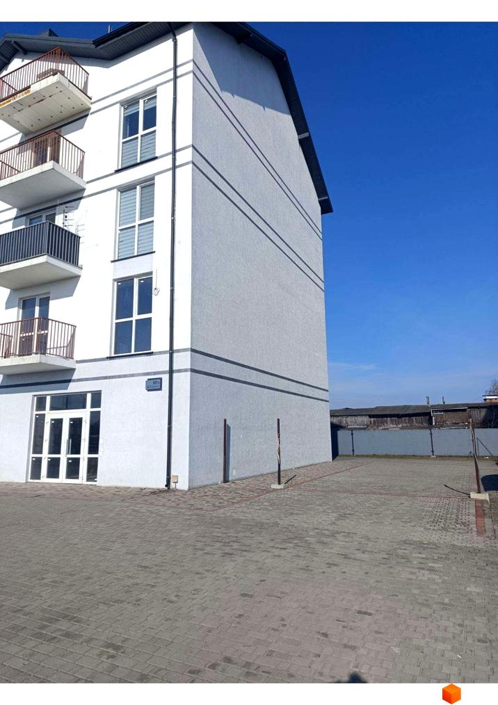 Багатоповерховий будинок Житлового комплексу Вижівський з білим фасадом, балконами та великими вікнами. Перед будинком розташована вимощена бруківкою територія.