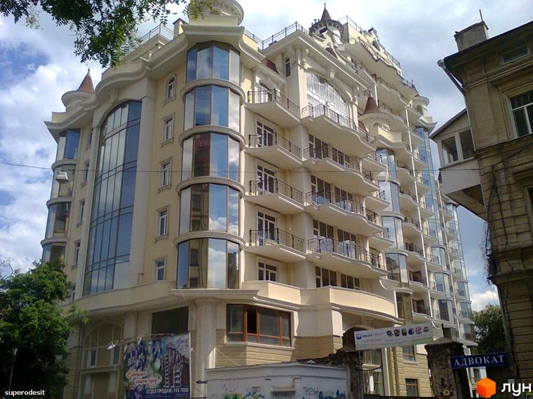 Житловий комплекс Замок цветов з великими вікнами та балконами. Прибудинкова територія озеленена деревами та кущами.