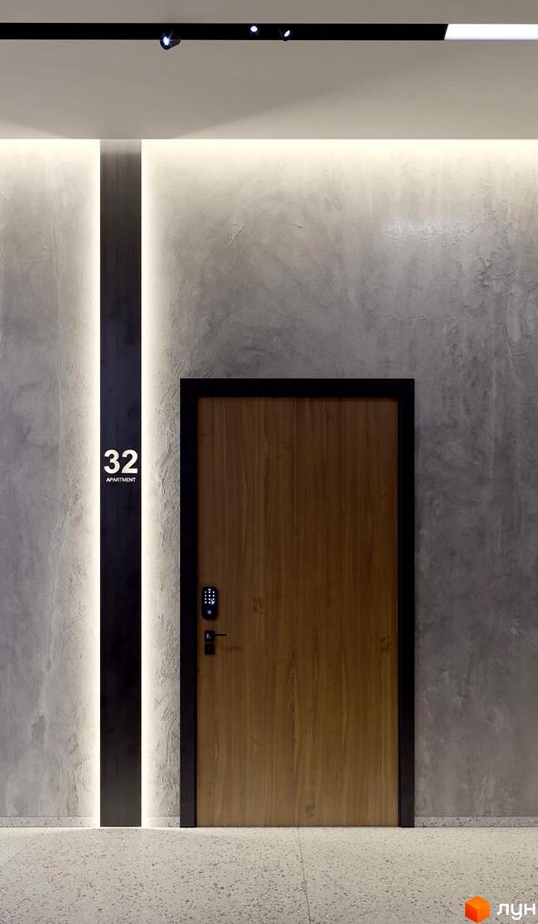 Вхідна група в апартаменти з дерев'яними дверима та цифровим замком. На стіні номер квартири 32.