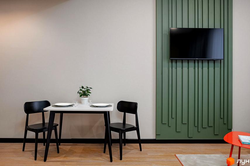 Інтер'єр квартири в Апарт-комплексі Kristal Plaza: обідній стіл з двома стільцями та телевізор на стіні з декоративними панелями.