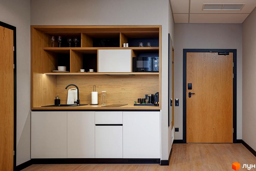Інтер'єр кухні в апартаментах Kristal Plaza. Дерев'яні шафи, білі фасади, чорна сантехніка та техніка. Двері з дерев'яним оздобленням.