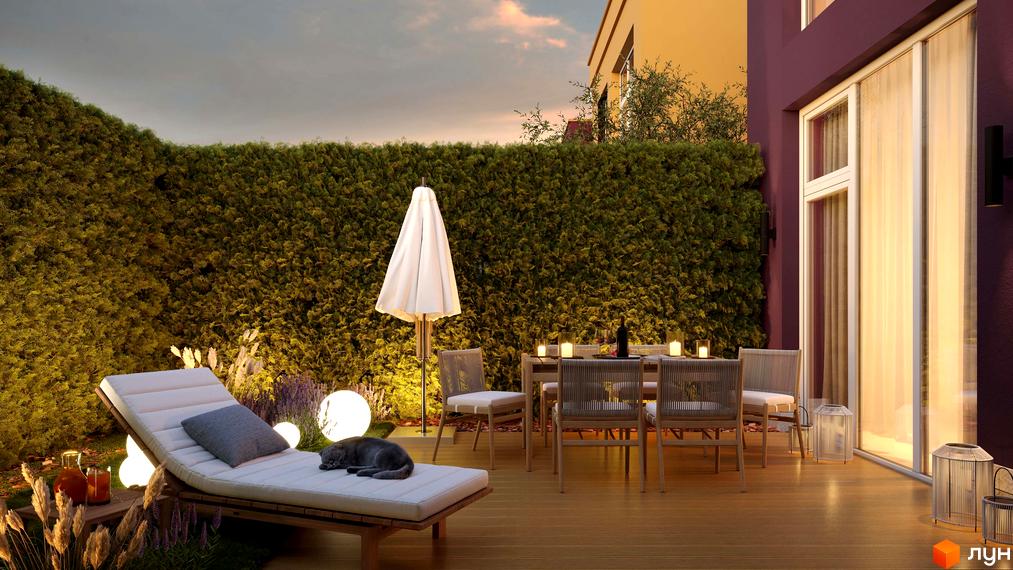 Затишна тераса в ЖК Cuvee Village з дерев'яною підлогою, зручним шезлонгом та столиком для відпочинку. Зелений газон та декоративне освітлення створюють атмосферу спокою.
