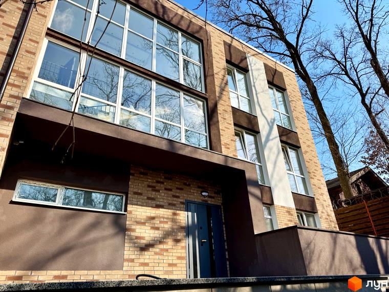 Зовнішній вигляд Клубного будинку Light Residence. Фасад будинку з великими вікнами та оздобленням з цегли.