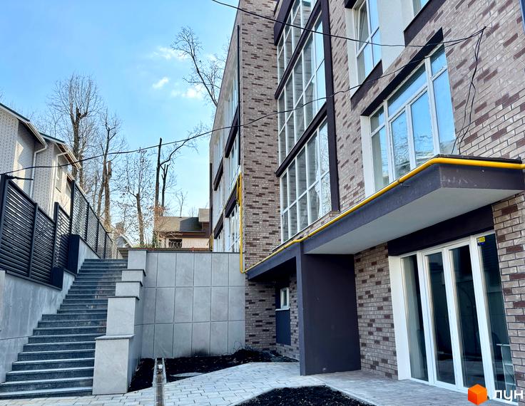 Зображення фасаду будинку в Житловому комплексі Light Residence з великими вікнами та сходами. Навколо будинку облаштована прибудинкова територія.