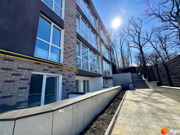 Зображення фасаду будинку Light Residence та прибудинкової території. На фото видно тротуарну доріжку та озеленену ділянку.