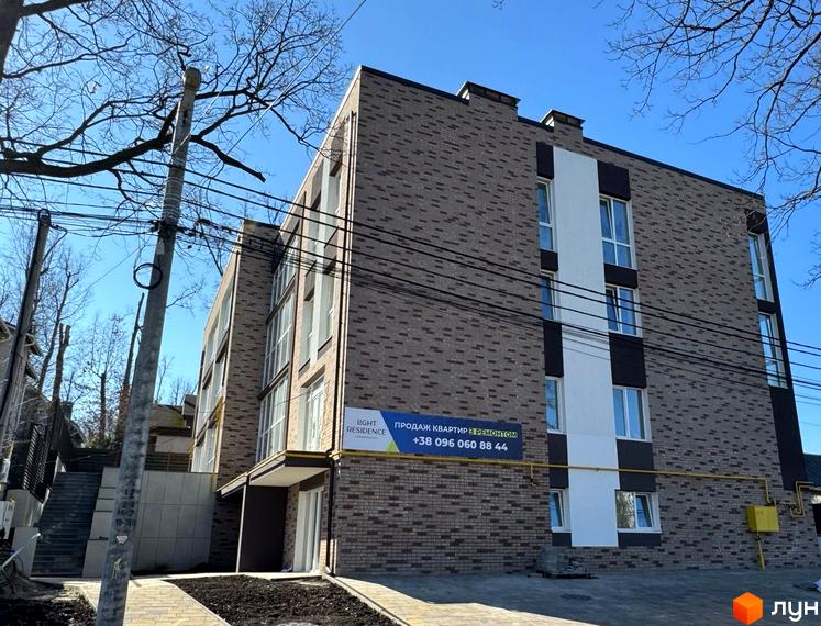 Новобудова Light Residence з цегляним фасадом та білими вертикальними елементами. Навколо будинку вимощена доріжка, сходи та дерева.