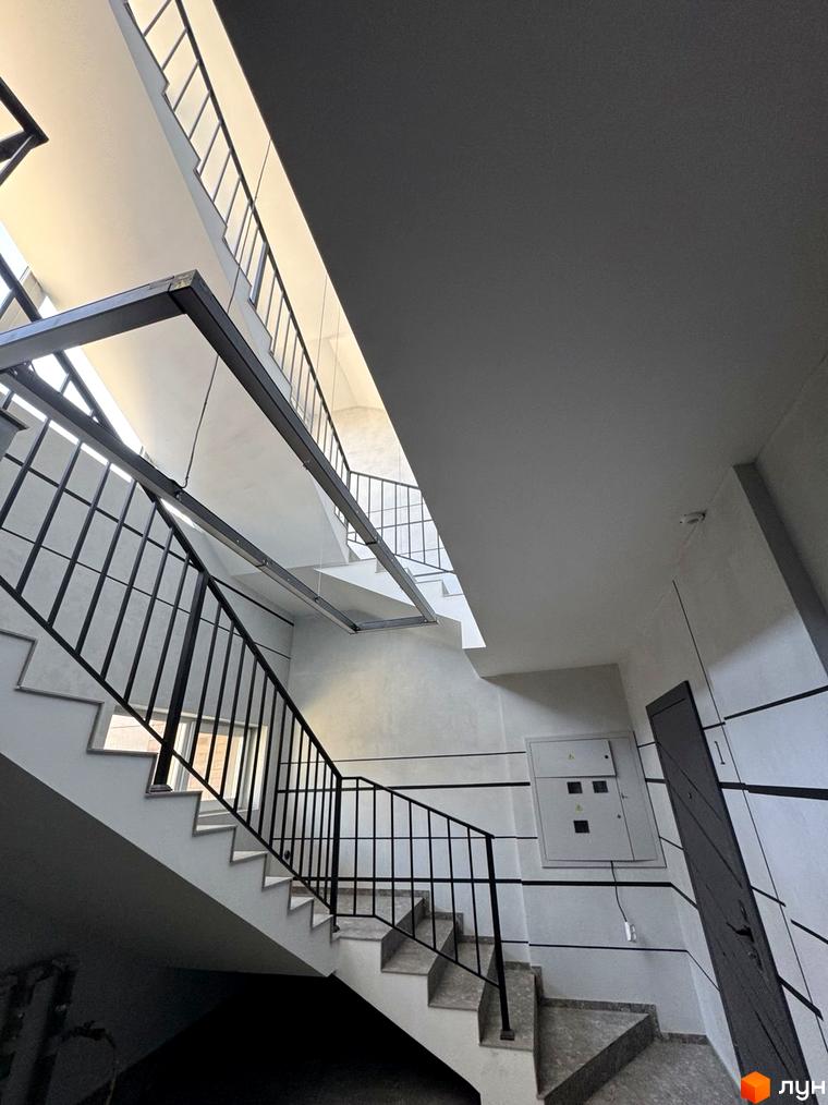 Фото сходового майданчика в Будівельному проєкті Light Residence. Сходи з чорними металевими поручнями.