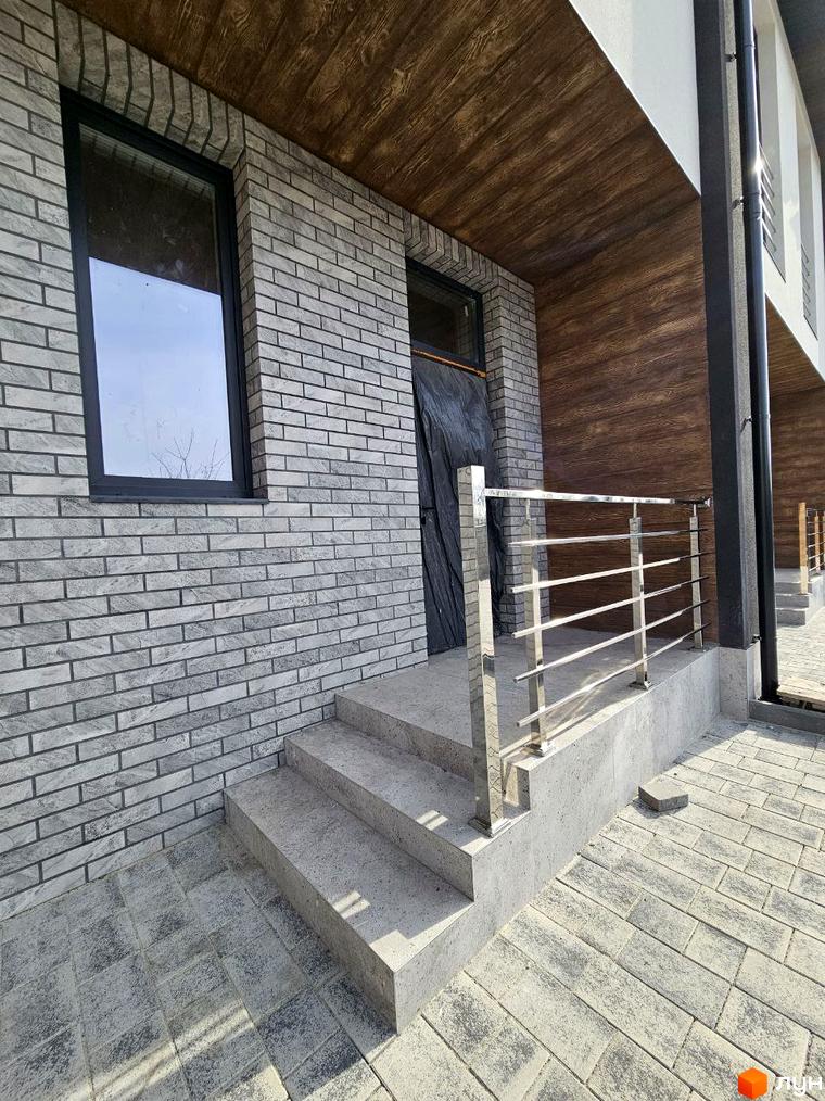 Зовнішній вигляд таунхаусу в Житловому районі „Дивногорський“ з оздобленням з цегли та дерев'яними елементами. Вигляд на сходи та металеві поручні.