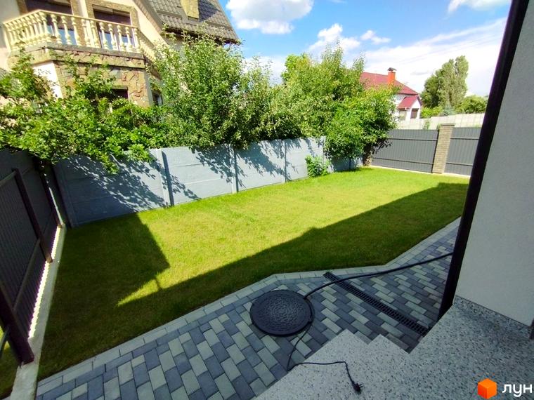 Зображення будинку з кам'яним фасадом та зеленим газоном на території новобудови за адресою вул. Івана Франка, 14.