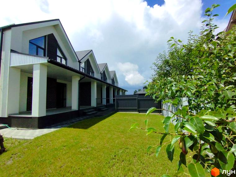 Котеджне містечко на вул. Івана Франка, 14: будинки з білими фасадами та темними дахами. Перед ними простягається доглянутий зелений газон.