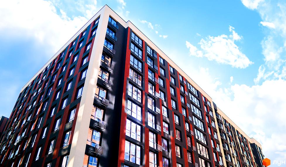 Зображення фасаду багатоповерхового будинку в Житловому комплексі Паркова Алея. Вигляд новобудови з великою кількістю вікон на тлі блакитного неба.