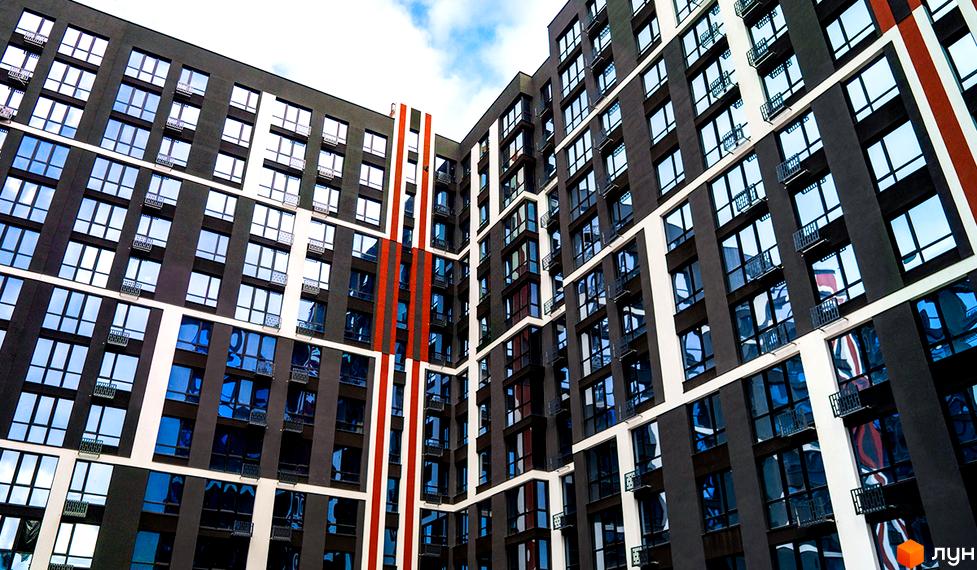 Багатоповерховий будинок ЖК U One з панорамними вікнами та балконами. Фасад будівлі виконаний у темних тонах з білими акцентами.