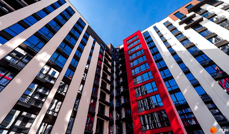Фасад новобудови ЖК Manhattan Up з червоними та білими елементами, багато вікон та балконів.