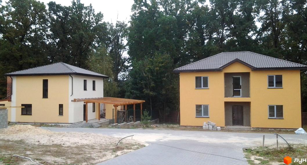 Котеджне містечко КМ Круглик: двоповерхові будинки жовтого та біло-жовтого кольору з сірими дахами. Навколо будівельний майданчик з піском та деревами.