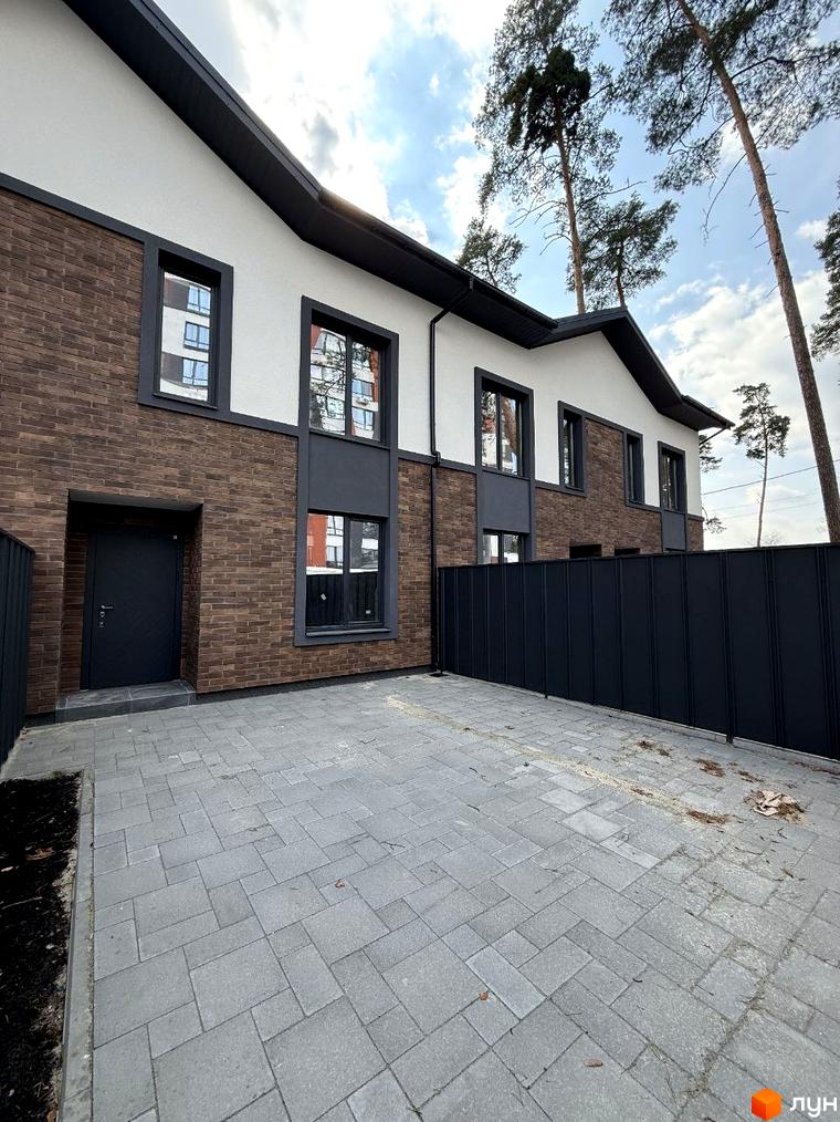 Зображення фасаду будинку та прибудинкової території Житлового комплексу на вулиці Павленка, 35. На передньому плані сіра бруківка.