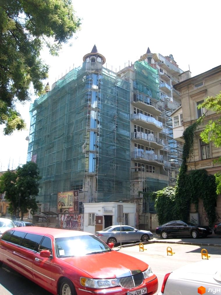 Житловий комплекс Замок цветов в процесі будівництва, з огорожею та прибудинковою територією. Вид на фасад з зеленими мережами.