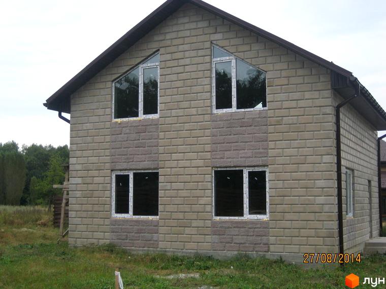 Будинок у Котеджному містечку Круглик: цегляний фасад, трикутні вікна на другому поверсі. Навколо будинку зелена територія.