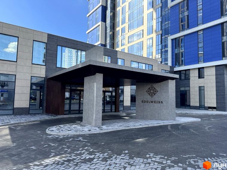 Зовнішній вигляд новобудови ЖК Edelweiss House з елегантною вхідною групою та сучасною архітектурою. Прибудинкова територія з бруківкою та зеленню.