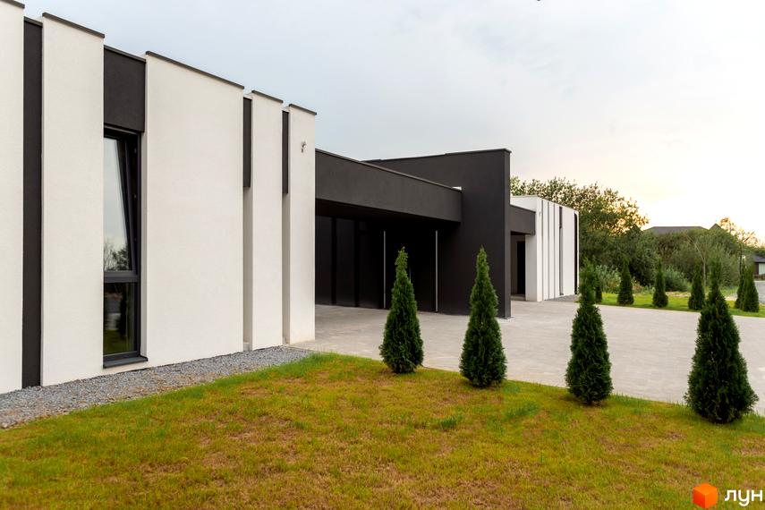 Зовнішній вигляд Duplex Comfort House з білими стінами та чорними вставками. На передньому плані газон з декоративними туями.