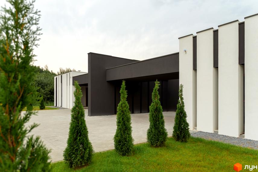 Зовнішній вигляд Duplex Comfort House. Будинок з чорними та білими стінами, перед будинком газон з туями.