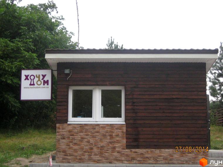 Котеджне містечко Круглик: фасад будинку з дерев'яною обшивкою та кам'яним цоколем, біля будинку зелена зона.