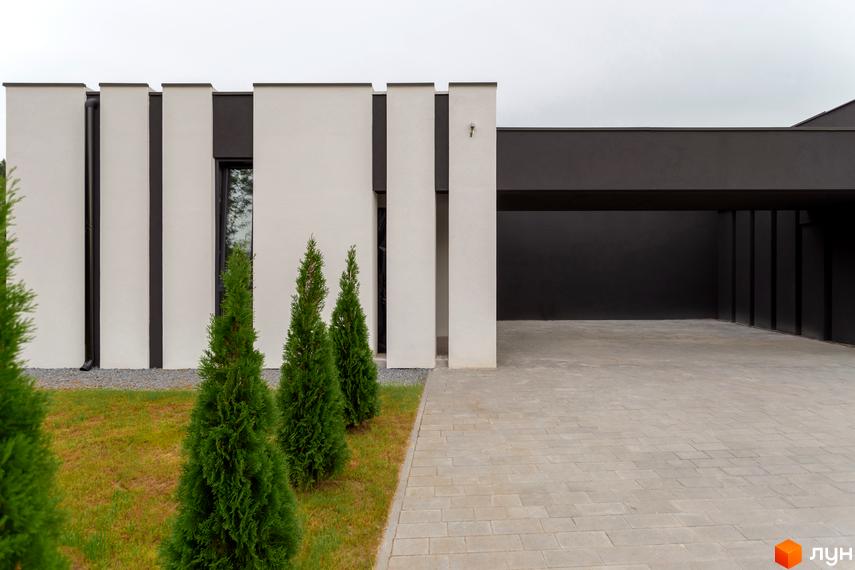 Зовнішній вигляд Duplex Comfort House з білими стінами та чорними вставками. На передньому плані зелені насадження та вимощена доріжка.