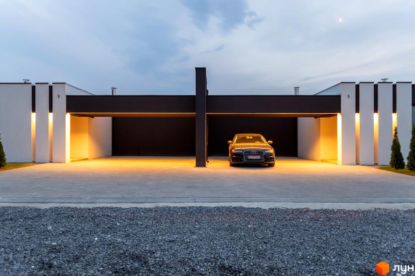 Зовнішній вигляд Duplex Comfort House з автомобілем на подвір'ї. Фасад будинку з підсвіткою та облаштована територія.