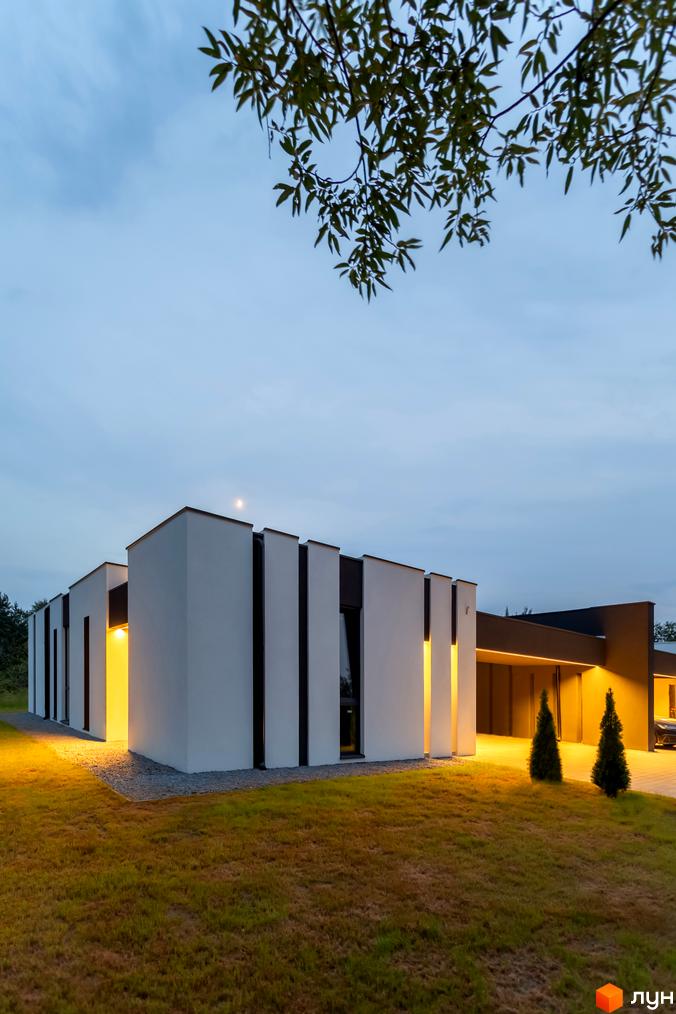 Duplex Comfort House – це новобудова з білим фасадом та темними вертикальними елементами, розташована на доглянутій галявині з освітленням.