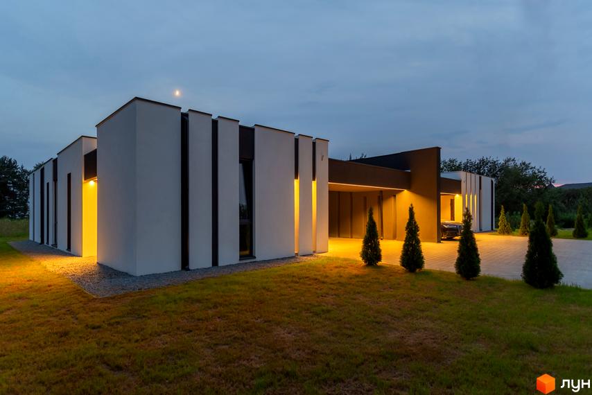 Житловий комплекс Duplex Comfort House з білими фасадами та великими вікнами, освітлення підкреслює архітектуру. На території газон та декоративні дерева.