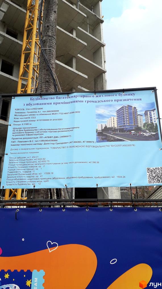 Будівництво житлового комплексу на вул. Чумацькій, 17-19. Багатоповерховий будинок з фасадом з скляних панелей та прибудинковою територією з зеленими насадженнями та дорогою.