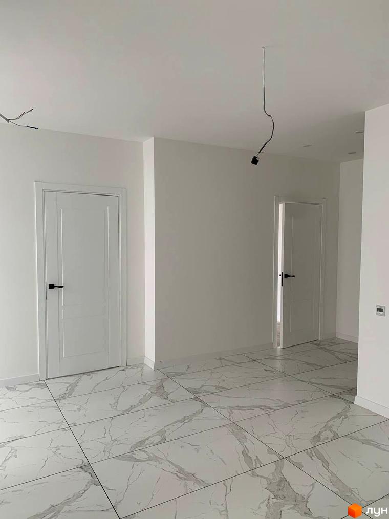 Клубний будинок „На Макіївській“: білі двері та мармурова підлога в новобудові. Просторий хол з двома дверима та підвішеним освітленням.