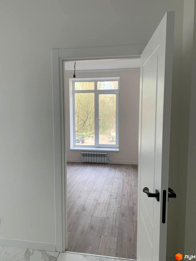 Клубний будинок „На Макіївській“: світлий коридор з білими дверима та видом на кімнату з великим вікном та дерев'яною підлогою.