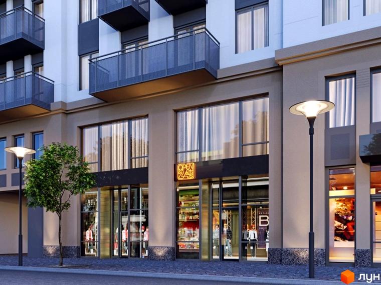 Фасад житлового комплексу Перший Французький з комерційними приміщеннями на першому поверсі та балконами на верхніх поверхах. Перед будинком розташована вулична лампа та дерево.