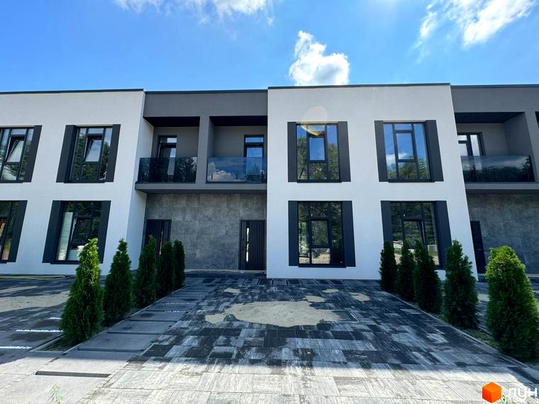 Фасад таунхаусів Osocor Apart, з великими вікнами та декоративними елементами. Перед будинком викладена плитка, ростуть туї.