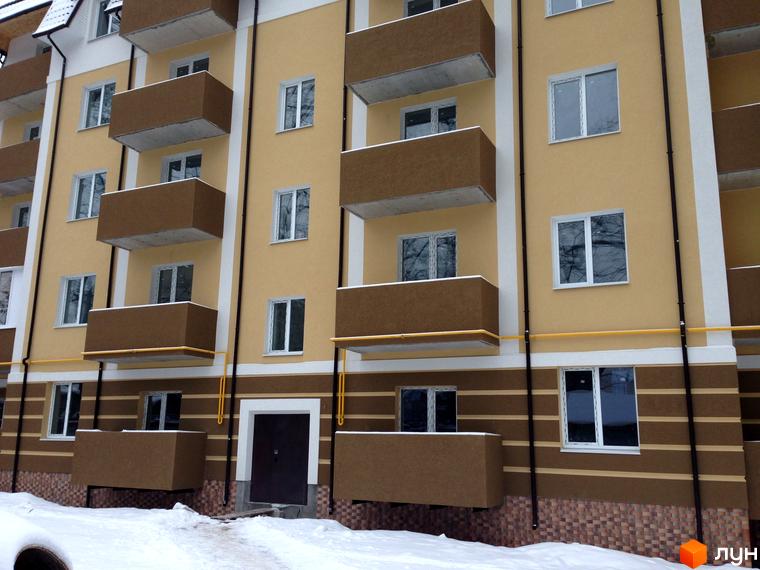 Зовнішній вигляд фасаду житлового комплексу Северинівський з балконами та вікнами. Навколо новобудови видно засніжену територію.