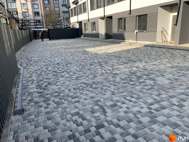 Фасад Таунхаусів „На Котляревського“ з сірими та білими елементами. Перед будинком викладена бруківка та встановлена огорожа.