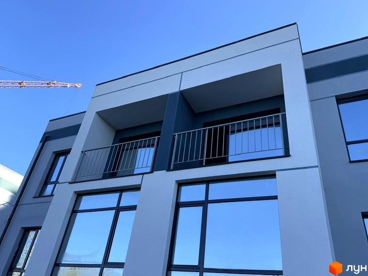 Зовнішній вигляд таунхаусів 4Family House з великими вікнами та балконами на тлі блакитного неба. На зображенні також видно будівельний кран.