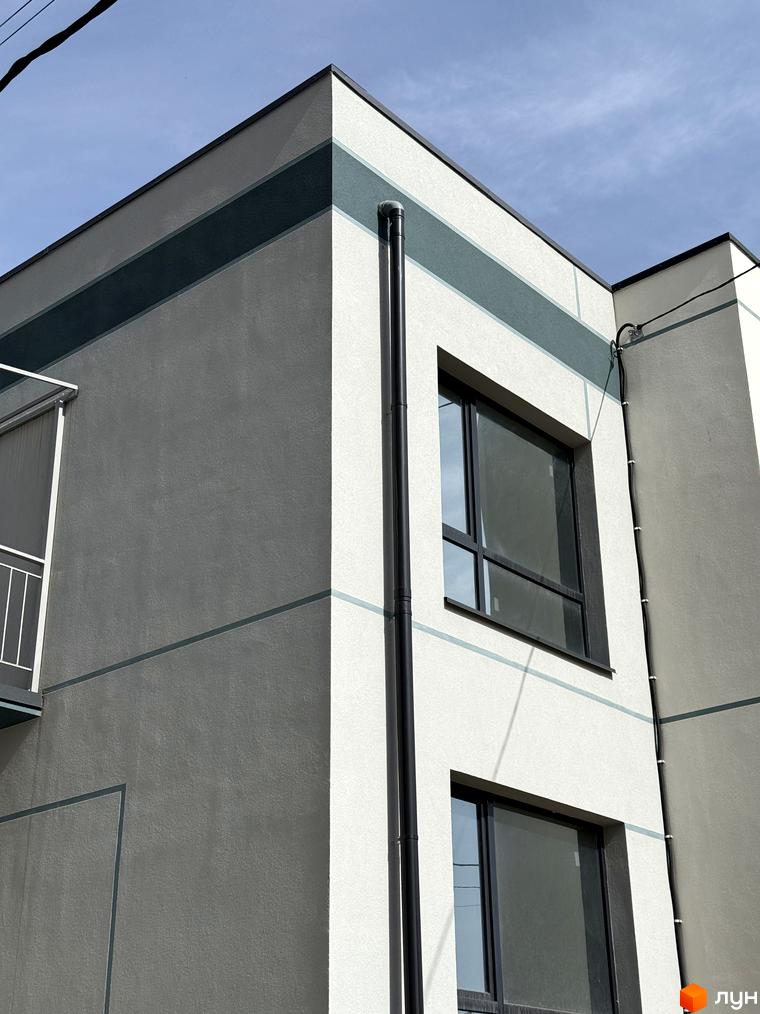 4Family House - новобудова з сірим фасадом та блакитними смугами, вікнами та зовнішнім водостічним жолобом.