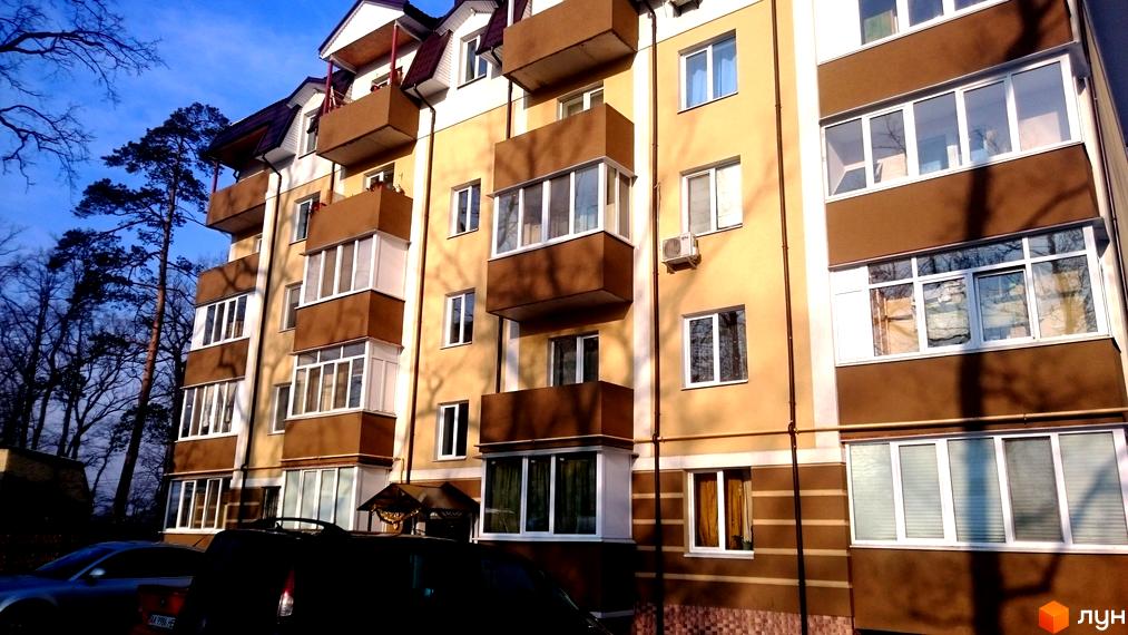 Житловий комплекс Северинівський. Фасад будинку з коричневими та бежевими елементами, балконами та великими вікнами. Навколо дерева та синє небо.