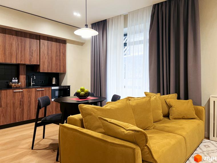 Апартаменти в Апарт-комплекс Крайобраз: функціональна кухня-вітальня з дерев'яними шафами, обідньою зоною та великим жовтим диваном.