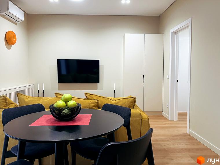 Вітальня в Апарт-комплексі Крайобраз з обідньою зоною, жовтим диваном, телевізором та шафою.