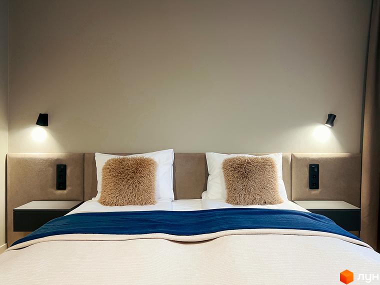 Затишна спальня в апартаментах житлового комплексу Крайобраз з двоспальним ліжком, подушками та нічниками.