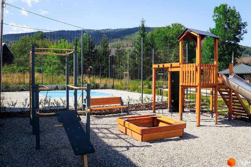 Прибудинкова територія Апарт-комплекс Крайобраз: дитячий майданчик з гіркою, пісочниця та спортивні тренажери.