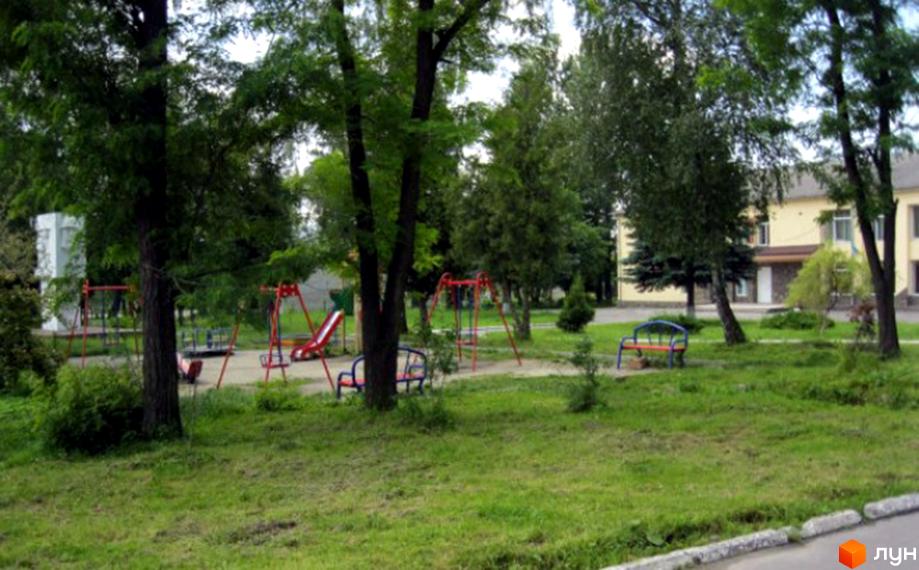 Дитячий майданчик біля житлового комплексу на вул. Центральна, 4а. Зелена прибудинкова територія з деревами та лавочками.