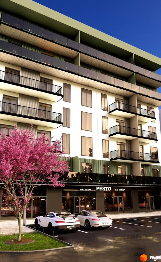 Житловий комплекс Home з балконами та магазинами на першому поверсі. Перед будинком припарковані білі автомобілі, росте дерево з рожевими квітами.