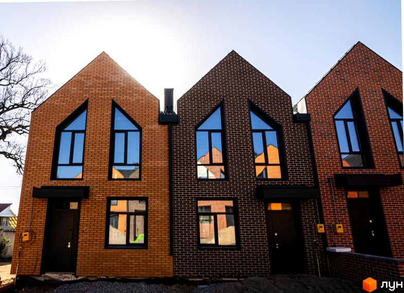 Зображення таунхаусів FORT HOMES з цегляними фасадами та великими вікнами. На передньому плані видно прибудинкову територію.