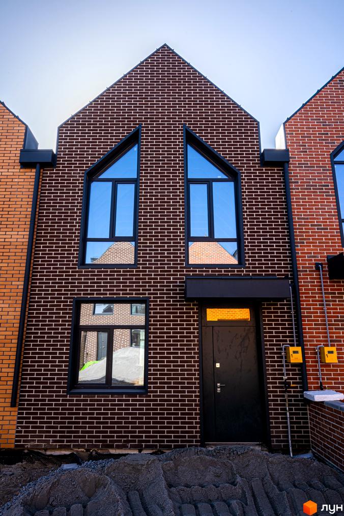 Фасад таунхауса в FORT HOMES з цегли з великими вікнами. Перед будинком насип з грунту.