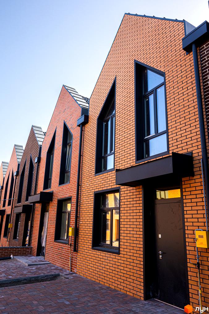 Зовнішній вигляд таунхаусів FORT HOMES з цегляним фасадом та великими вікнами. Вигляд на прибудинкову територію.